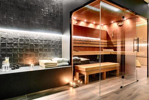 a bathroom with a glass shower with a bench and a sink at Hotel The Loom in Łódź