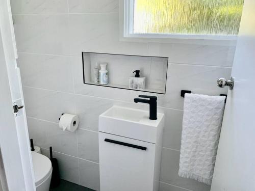 a white bathroom with a sink and a toilet at Tynedale Cottage Bowral in Bowral