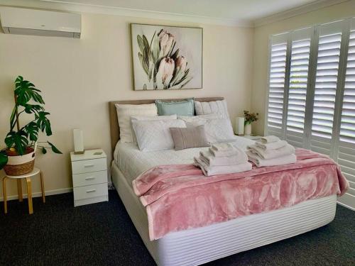sypialnia z dużym łóżkiem z różową pościelą i poduszkami w obiekcie Tynedale Cottage Bowral w mieście Bowral