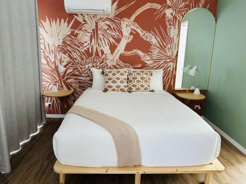 a bedroom with a white bed with a tropical wallpaper at Tessa's on the Beach in Gold Coast