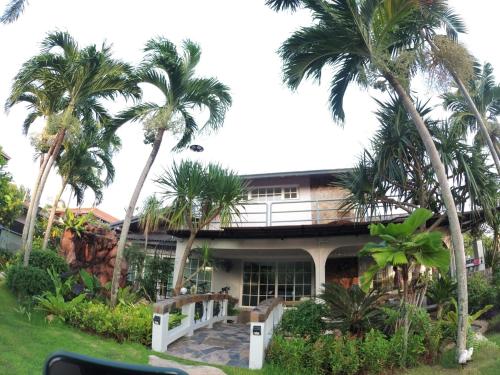 a house with palm trees in front of it at Let's Chill Pool Villa Pattaya Najomtien42 and Sattahip in Ban Tao Than