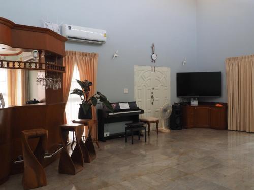 a living room with a piano and a television at Let's Chill Pool Villa Pattaya Najomtien42 and Sattahip in Ban Tao Than