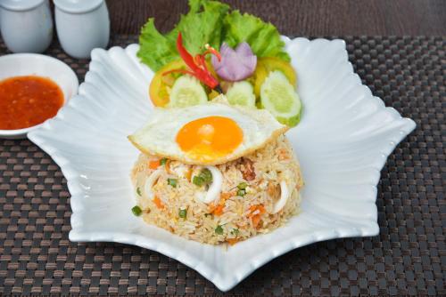 een wit bord met een ei, rijst en salade bij 360 Resort in Sihanoukville