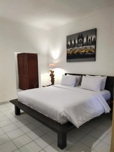 1 dormitorio con 1 cama grande con sábanas blancas en La Walon Hotel en Kuta