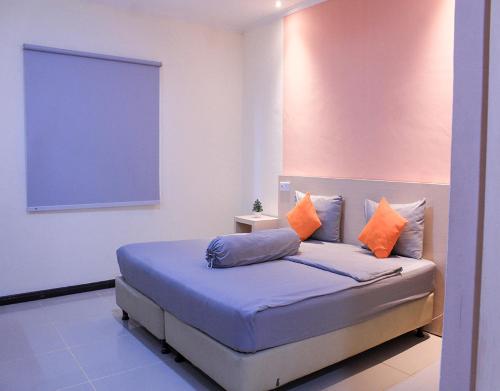 a bedroom with a bed with orange and blue pillows at Suzuya Hotel Bagan Batu in Bagansinembah
