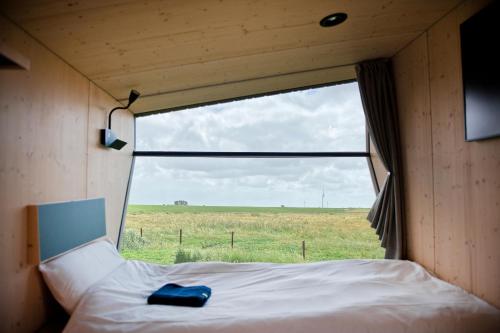 uma cama num pequeno quarto com uma grande janela em Sleep Space 21 - Green Tiny Village Harlesiel em Wittmund