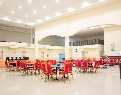 a large room with tables and red chairs at Suzuya Hotel Bagan Batu in Bagansinembah