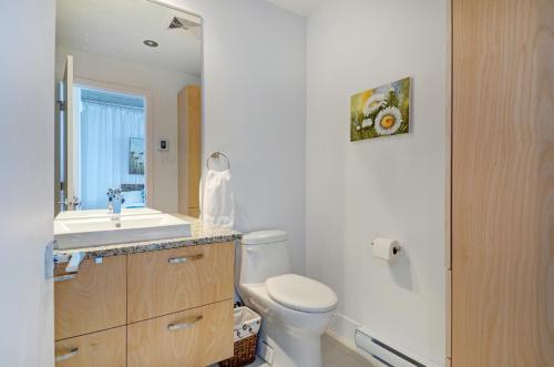 La salle de bains est pourvue de toilettes blanches et d'un lavabo. dans l'établissement Les Immeubles Charlevoix - Le 760314, à Québec