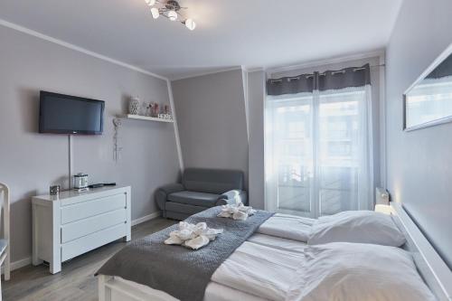 a bedroom with a bed and a tv and a chair at Regina Maris by Baltic Home in Świnoujście