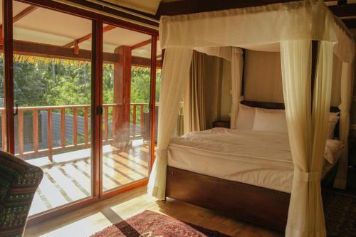 a bedroom with a canopy bed and a balcony at Domu Mia Villa Siargao in General Luna