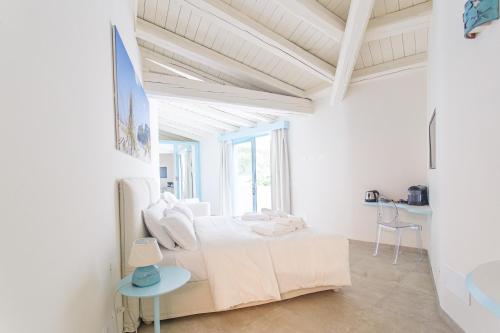 a white bedroom with a bed and a table at Oasi Blu Sardinia in Santa Margherita di Pula
