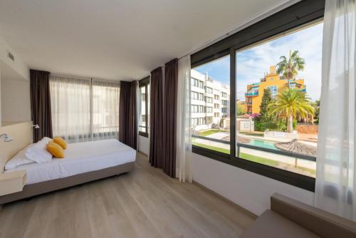 1 dormitorio con cama y ventana grande en Atenea Park Suites & Apartments, en Vilanova i la Geltrú