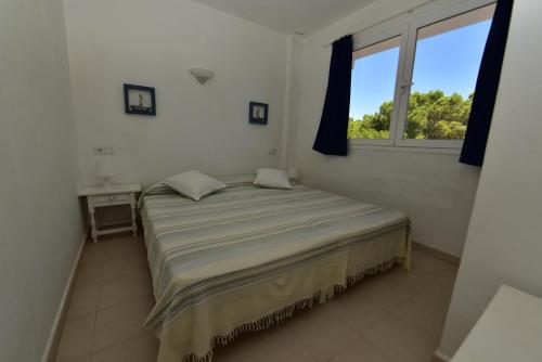 1 dormitorio con 1 cama grande y ventana en Pujols 15 en Es Pujols