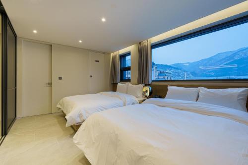 two beds in a bedroom with a large window at Eden Foret Hotel in Chungju