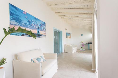 a living room with white furniture and a large painting on the wall at Oasi Blu Sardinia in Santa Margherita di Pula