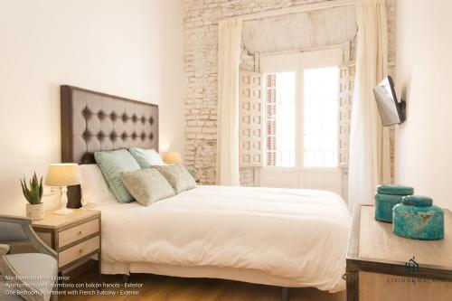 Living4Malaga Boutique Apartments في مالقة: غرفة نوم بسرير ابيض كبير ونافذة