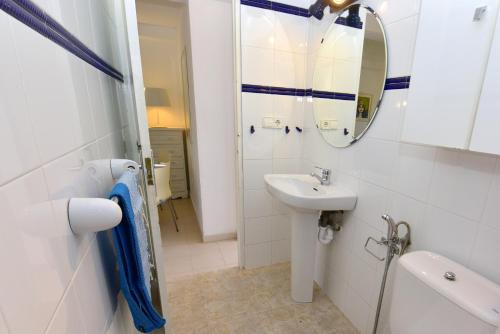 uma casa de banho branca com um lavatório e um espelho em Pujols 15 em Es Pujols