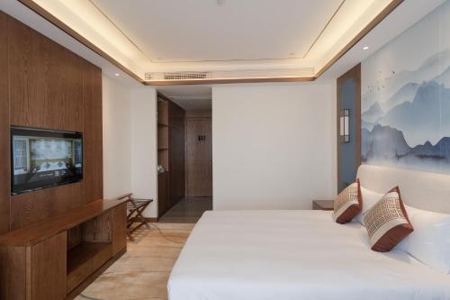 a hotel room with a bed and a tv at S&N Xuanting Hotel Pengze in Pengze