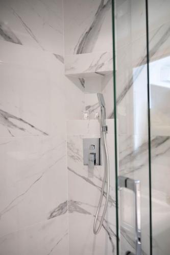 La salle de bains est pourvue d'une douche et de murs en marbre blanc. dans l'établissement MONACO SEA VIEW APARTMENTS, à Beausoleil