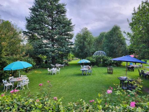 a garden with tables and chairs and umbrellas at Green Lantern Inn in Van Reenen