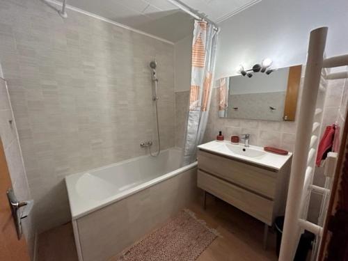 uma casa de banho com uma banheira e um lavatório e uma banheira em Appartement 6/8 personnes 