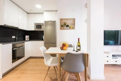 a kitchen with a table with chairs and a bottle of wine at Apartamento con jardin privado y portero (B) in Madrid