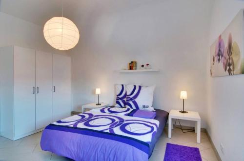 1 dormitorio con 1 cama de color púrpura y 2 lámparas en Ferienwohnung Hornisgrindeblick, en Obersasbach
