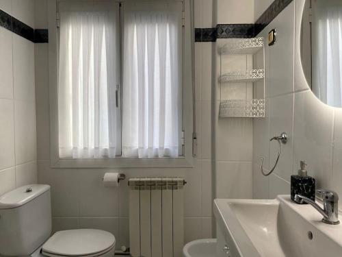 a white bathroom with a toilet and a sink at 80 m2 recién reformado, acogedor y elegante. in Balmaseda