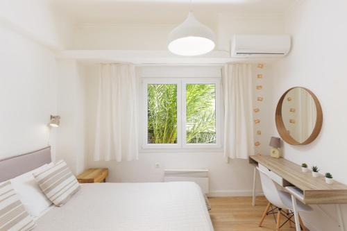 a bedroom with a bed and a desk and a window at Aloe Apartments in Corfu