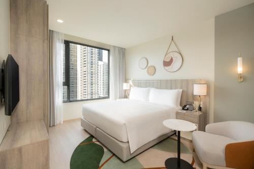 a hotel room with a white bed and a couch at Staybridge Suites Bangkok Sukhumvit by IHG in Bangkok