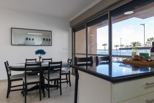 cocina y comedor con mesa y sillas en O&O Group - Stylish & Cozy Seaview Vacation APT, en Bat Yam