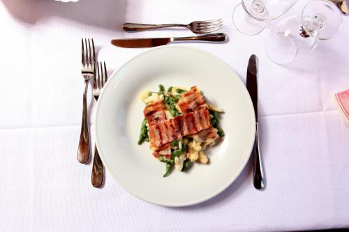 a white plate with food on a white table with silverware at GH Hotel Fratazza in San Martino di Castrozza