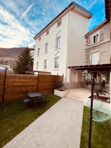 un patio avec une table et des chaises devant un bâtiment dans l'établissement Appartement Proche Hôpital La Tronche, à La Tronche