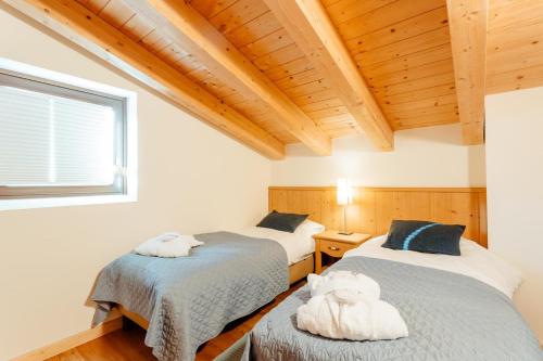 two beds in a room with wooden ceilings at Apartment Alexander by MoniCare in Seefeld in Tirol