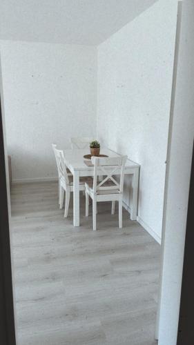 una mesa y sillas blancas en una habitación blanca en Ferienwohnung Frieda, en Delmenhorst