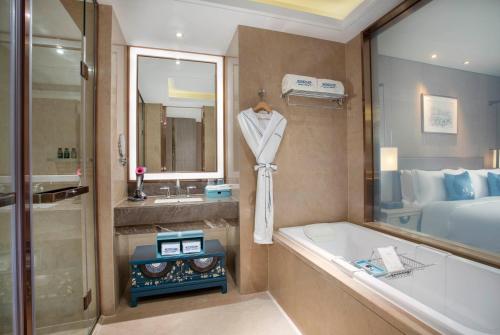 a bathroom with a tub and a sink and a bed at Kunming Huiyue Wyndham Hotel in Kunming