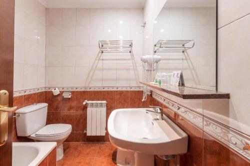 a bathroom with a sink and a toilet and a mirror at Hotel Puerta de Javalambre in La Puebla de Valverde