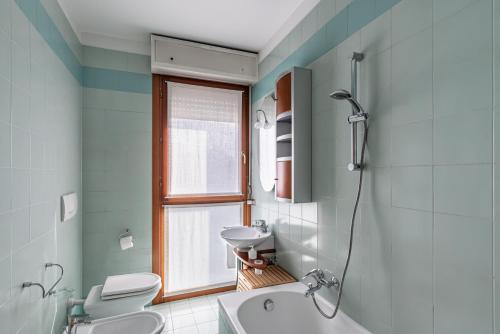 een badkamer met een wastafel, een toilet en een raam bij Padova Palestro Pastel Apartment in Padua