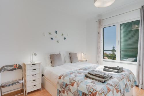 Un dormitorio blanco con una cama y una ventana. en Alta do Garajau II, en Caniço