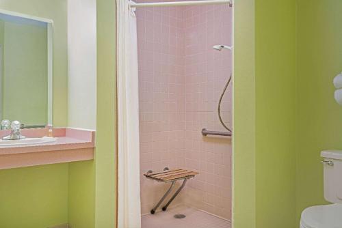 y baño con ducha de azulejos rosados. en Days Inn by Wyndham West-Eau Claire en Eau Claire