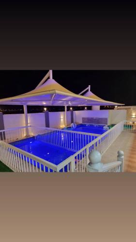 a large swimming pool on a house at night at Smart Chalet:سمارت شالية in Salalah