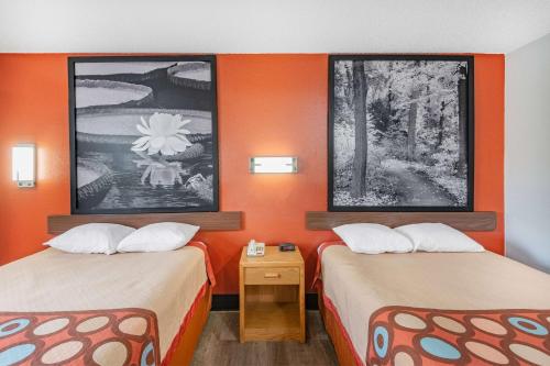 two beds in a small room with orange walls at Super 8 by Wyndham Waynesburg in Waynesburg