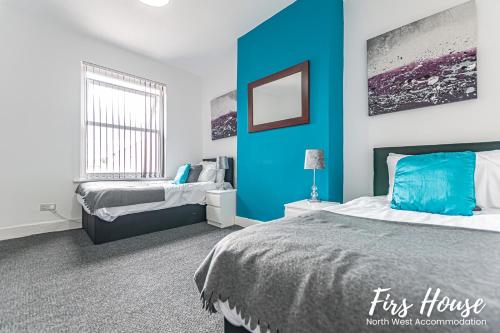 リーにあるFirs Serviced Accommodationの青いアクセントの壁のベッドルーム1室、ベッド2台が備わります。