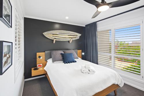 a bedroom with a bed with a surfboard on the wall at Ocean View Apartment - Aqualuna Coffs Harbour in Sapphire Beach