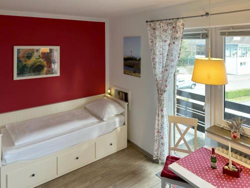 ein Schlafzimmer mit einem Bett mit einer roten Wand in der Unterkunft Haus Diana *Ferienwohnung Wattenmeer* in Wittdün
