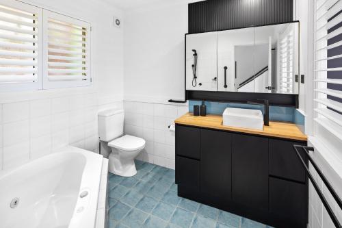 a bathroom with a tub and a toilet and a sink at Ocean View Apartment - Aqualuna Coffs Harbour in Sapphire Beach