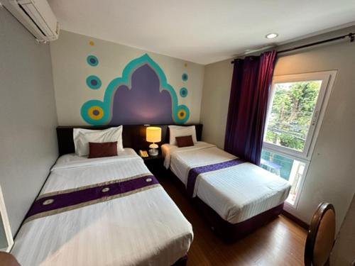 een slaapkamer met 2 bedden en een raam bij Sawasdee Hotel @ Sukhumvit Soi 8 in Bangkok