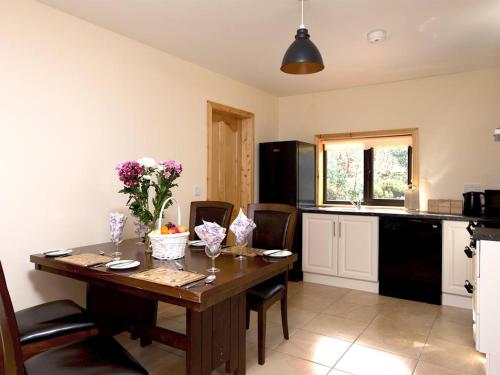 a kitchen with a wooden table with flowers on it at Fern Wood Estate in Glengarriff