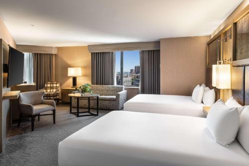 ボストンにあるハイアット リージェンシー ボストンのベッド2台とリビングルームが備わるホテルルームです。