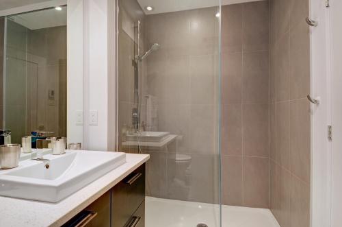 a bathroom with a sink and a glass shower at Les Immeubles Charlevoix - Le 760-431 in Quebec City